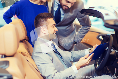 Image of happy couple with car dealer in auto show or salon