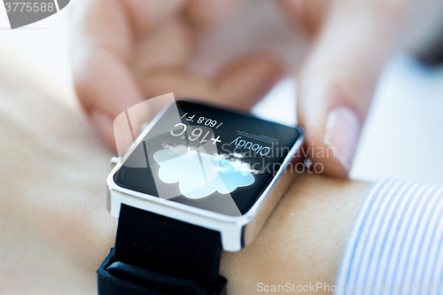 Image of close up of hands with weather icon on smartwatch