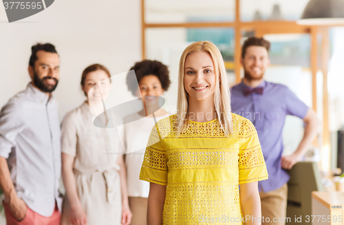Image of happy young woman over creative team in office