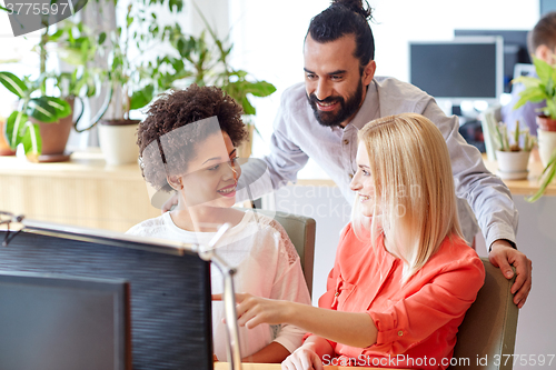 Image of happy creative team with computer in office
