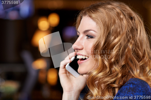Image of young woman with smartphone at night club or bar