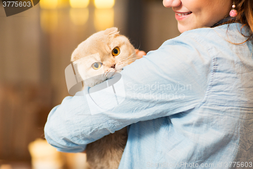 Image of happy woman holding scottish fold cat at home