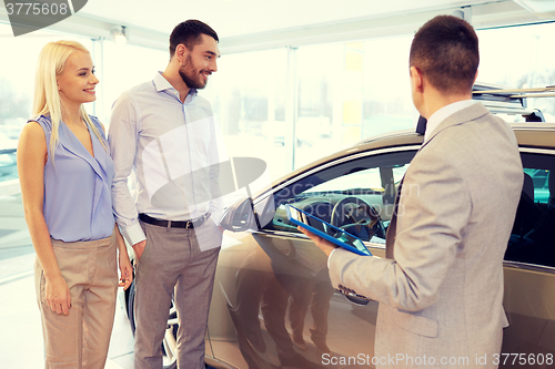 Image of happy couple with car dealer in auto show or salon