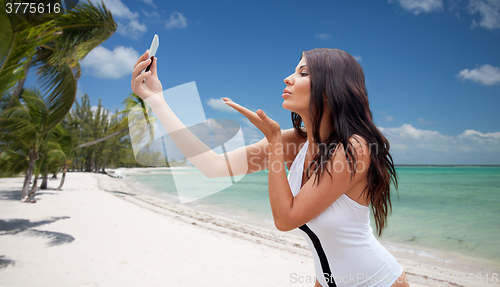 Image of young woman taking selfie with smartphone