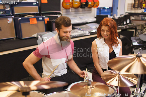 Image of happy man and woman playing cymbals at music store