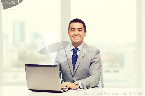 Image of smiling businessman with laptop and papers