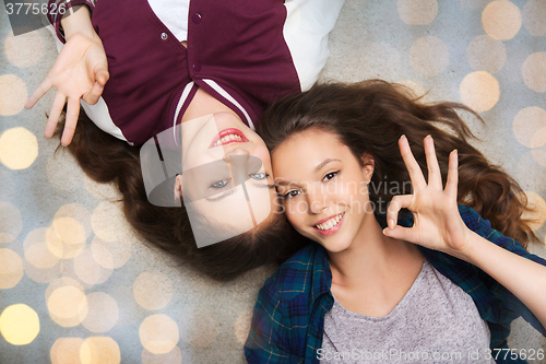 Image of happy smiling pretty teenage girls lying on floor