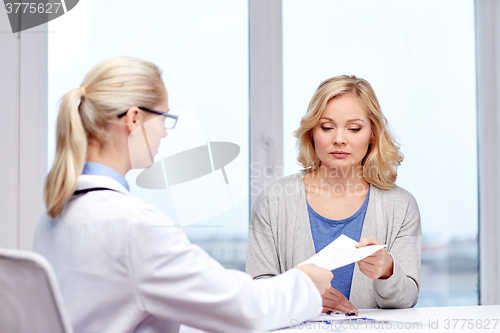 Image of doctor giving prescription to woman at hospital