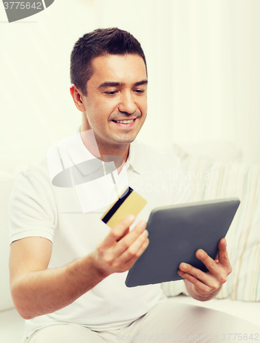 Image of smiling man working with tablet pc at home