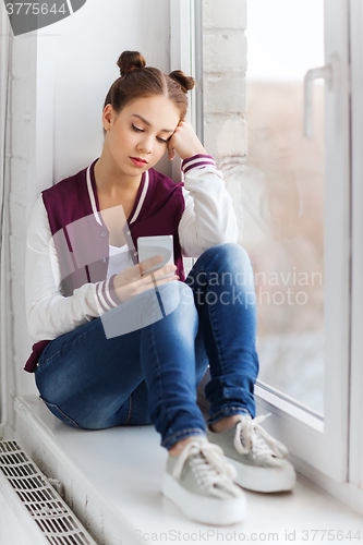 Image of sad pretty teenage girl with smartphone texting