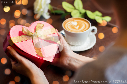 Image of close up of hands holding heart shaped gift box