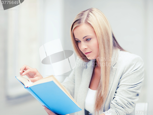 Image of young woman reading book at school