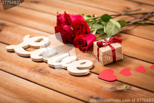 Image of close up of gift, word love, red roses and hearts