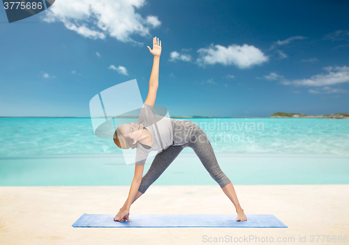 Image of woman making yoga triangle pose on mat