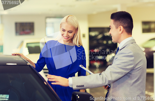 Image of happy woman with car dealer in auto show or salon