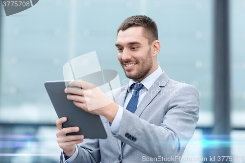 Image of smiling businessman with tablet pc outdoors