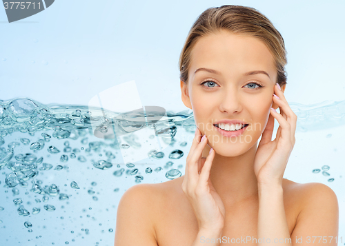 Image of smiling young woman touching her face