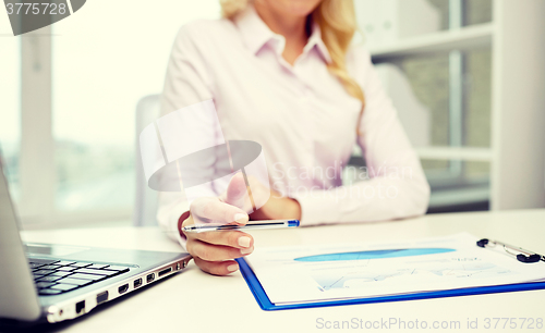 Image of smiling businesswoman reading papers in office