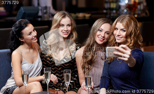 Image of women with champagne taking selfie at night club