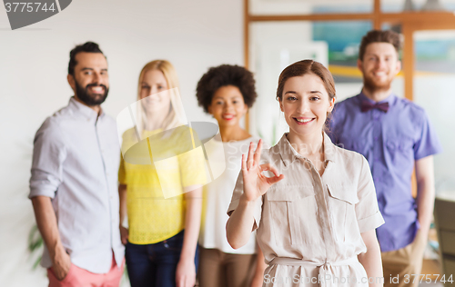 Image of happy woman showing ok over creative office team