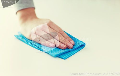 Image of close up of hand cleaning table surface with cloth