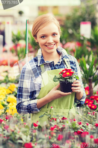 Image of happy woman holding flowers in greenhouse