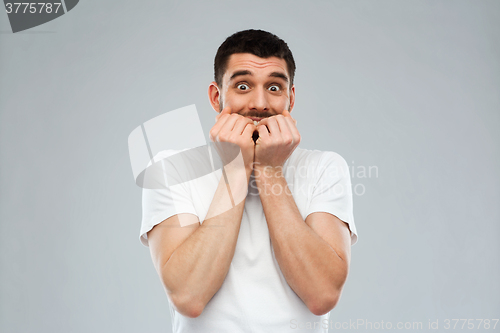 Image of scared man in white t-shirt over gray background