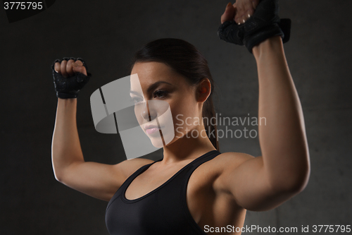 Image of young woman flexing muscles in gym