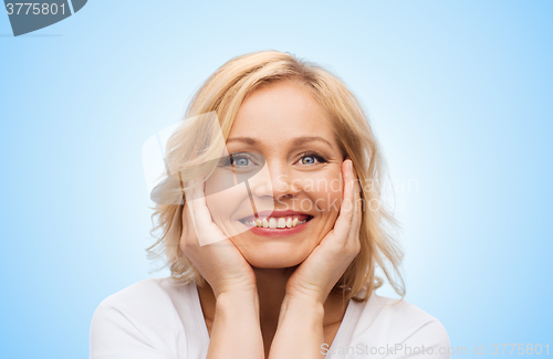 Image of smiling woman in white t-shirt touching her face