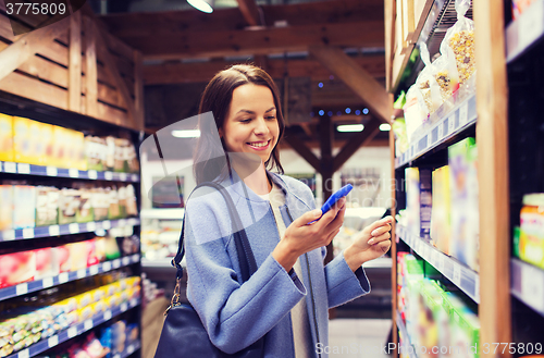 Image of happy young woman with smartphone in market