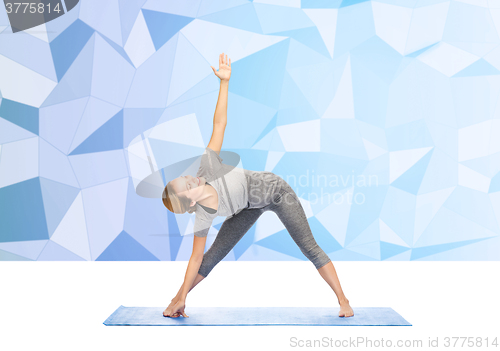 Image of woman making yoga triangle pose on mat