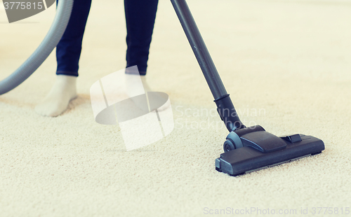 Image of close up of woman legs with vacuum cleaner at home