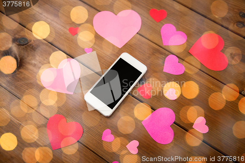 Image of close up of smartphone and hearts on wood