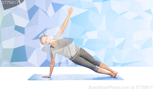 Image of woman making yoga in side plank pose on mat