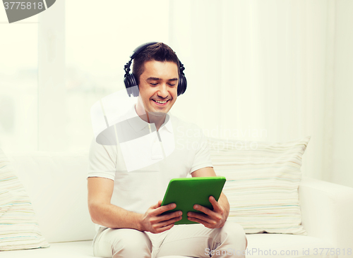 Image of smiling man with tablet pc and headphones at home