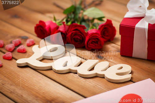 Image of close up of gift box, red roses and greeting card