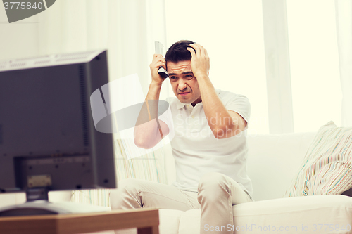 Image of disappointed man watching tv at home
