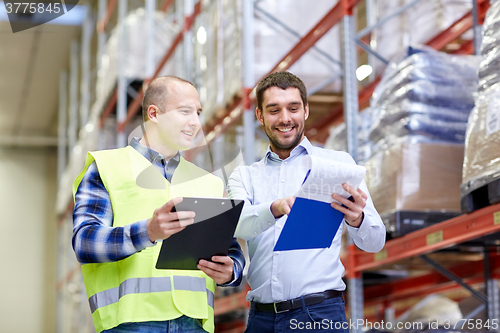 Image of worker and businessmen with clipboard at warehouse