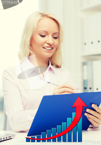 Image of happy businesswoman writing to clipboard in office