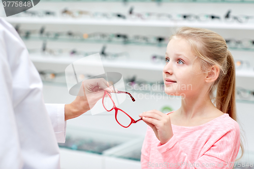 Image of optician giving glasses to girl at optics store