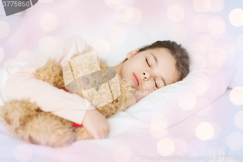 Image of girl sleeping with teddy bear toy in bed at home