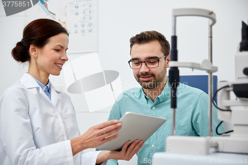 Image of optician with tablet pc and patient at eye clinic