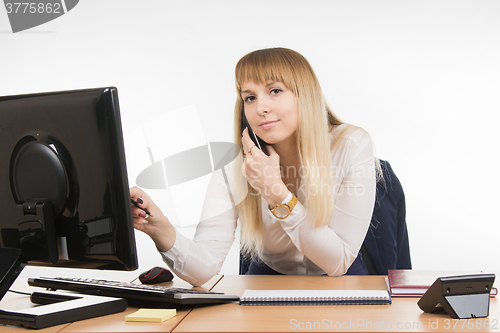 Image of  Business woman working on the computer, talking on the phone and looked at the frame