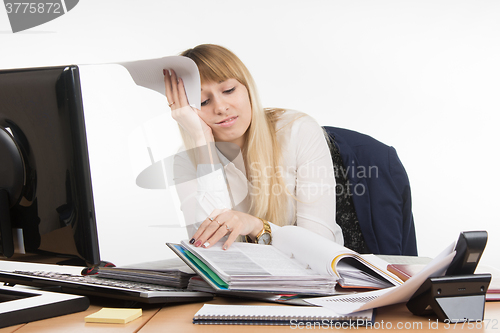 Image of Frustrated and tired woman in the office leafing through a folder with papers