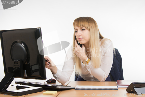 Image of Business woman with concentration works in the computer while talking on the phone