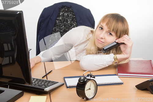 Image of Tired office employee lying on the desk talking on the phone and looked at the frame