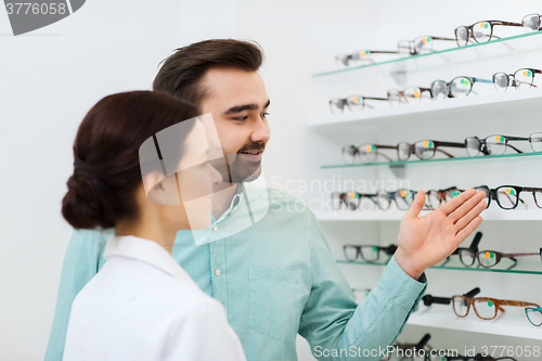 Image of optician and man choosing glasses at optics store