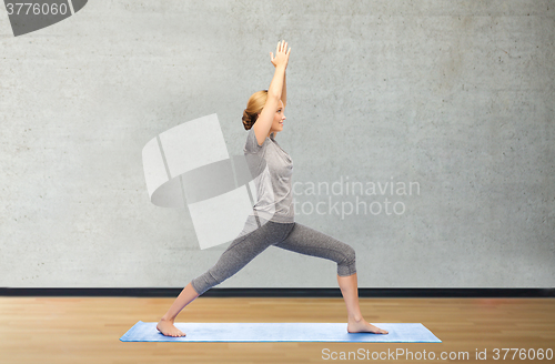 Image of woman making yoga warrior pose on mat