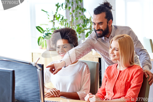 Image of happy creative team with computer in office