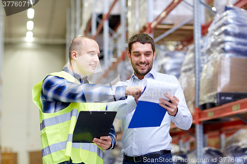 Image of worker and businessmen with clipboard at warehouse